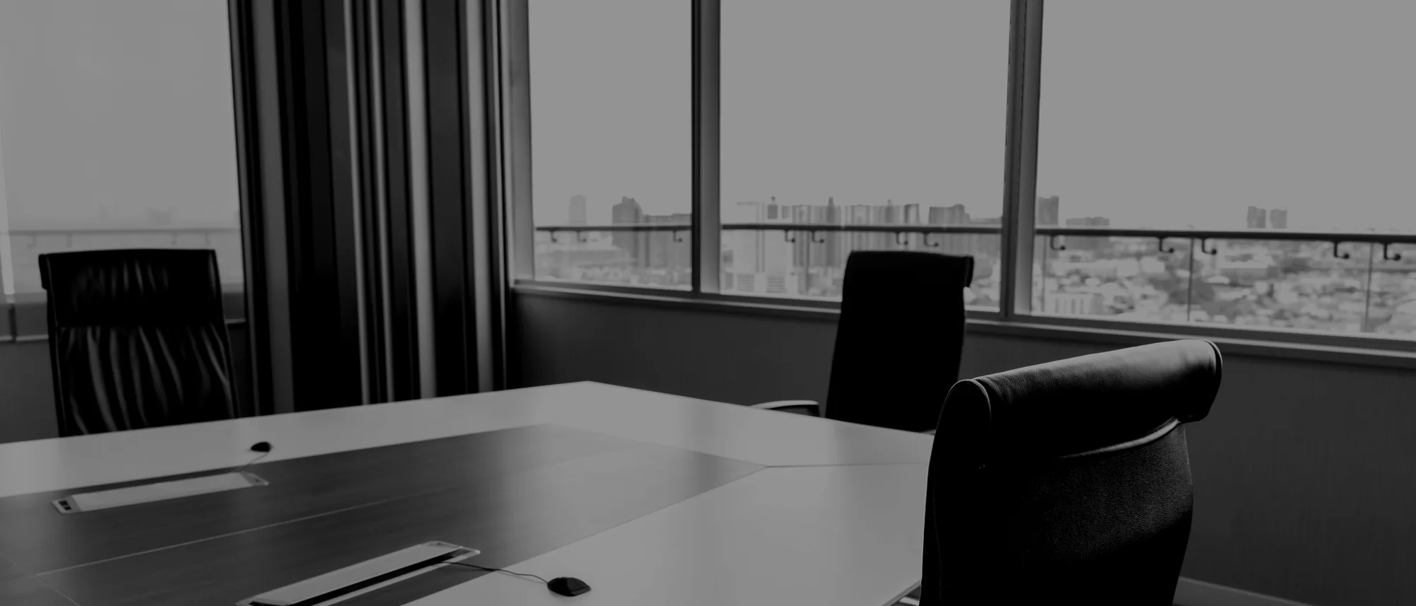 An empty boardroom table with the city beyond the glass