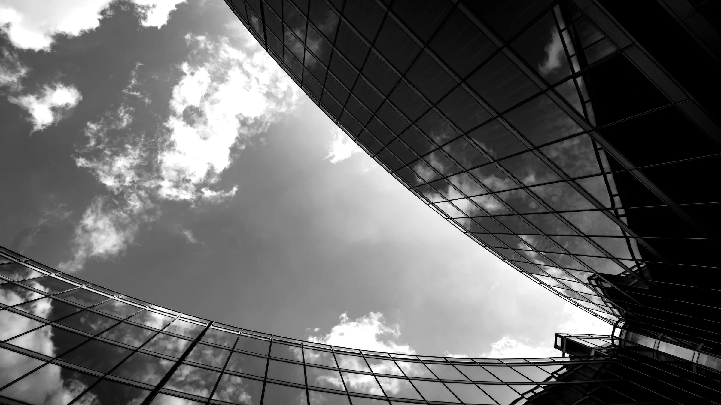 A curved glass roof sweeping across open sky, seen from below