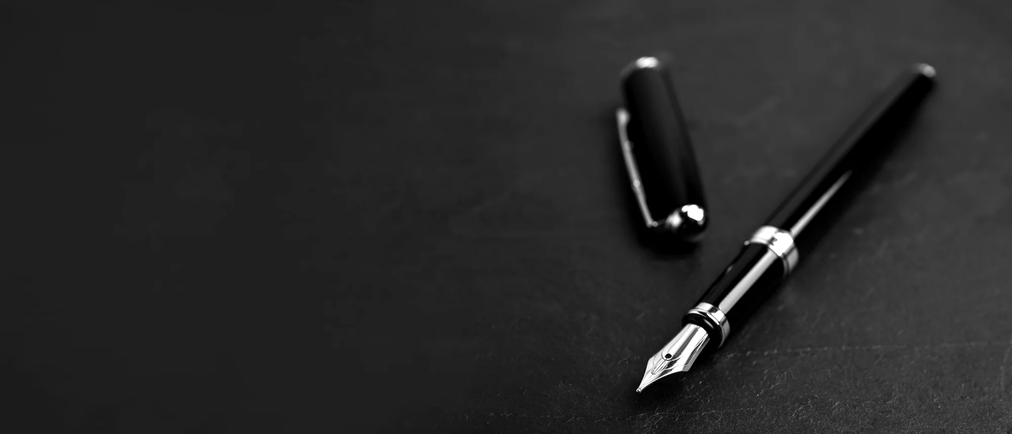 A fountain pen resting on a dark desk