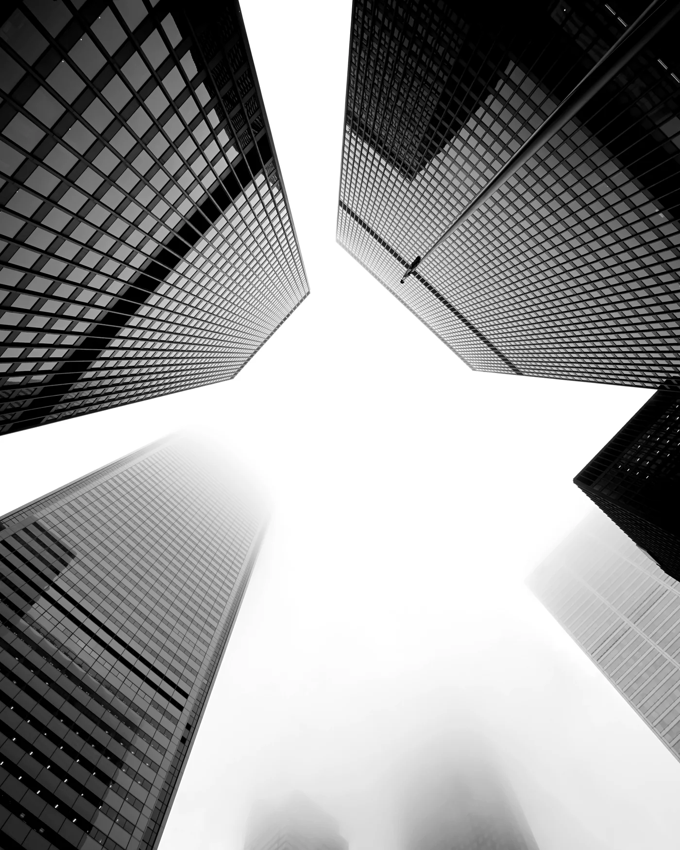 Office towers converging toward a bright opening of sky